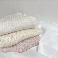 three blankets stacked on top of each other next to a white pillow and blanket cover