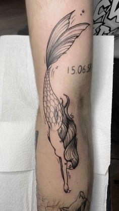 a tattoo on the leg of a person with a fish in it's tail