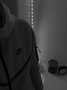 black and white photograph of a person in the mirror with their hoodie pulled up