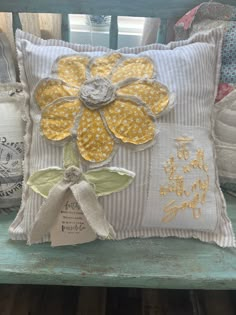 a yellow flower on a white pillow sitting on a bench