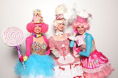 three women dressed in colorful costumes posing for a photo with lollipop hats and candy canes