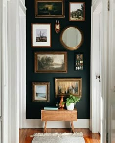 a hallway with pictures on the wall and paintings on the wall, along with a rug