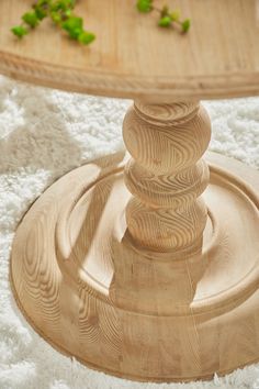 a round wooden table sitting on top of a white fluffy rug next to a coffee table