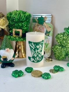 a white candle sitting on top of a table next to shamrocks and other decorations