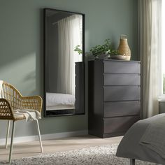 a bedroom scene with focus on the dresser and bed in the foreground, and an empty chair to the side