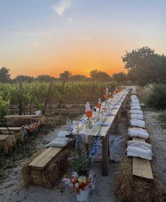 a long table is set up in the middle of a field with hay bales