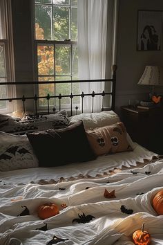 a bed covered in white sheets with pumpkins on the bottom and sides, next to a window