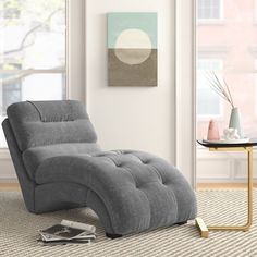 a living room with a gray reclining chair next to a coffee table and window