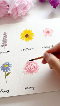 someone is painting flowers with watercolors on paper and writing them in the same language