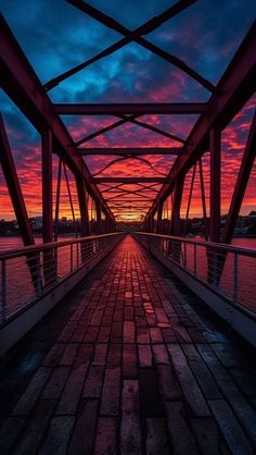 the sun is setting over a bridge with water and brick walkways leading to it