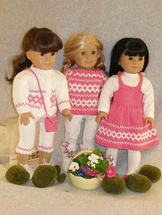 three dolls standing next to each other in front of a basket with flowers on it