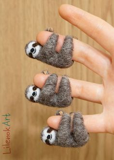 two small stuffed animals sitting on top of each other's fingers in front of a wooden table