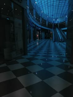 an escalator in the middle of a large building with checkered flooring