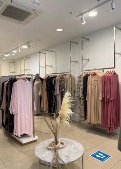 a clothing store filled with lots of different colored shirts and dresses on display next to a table