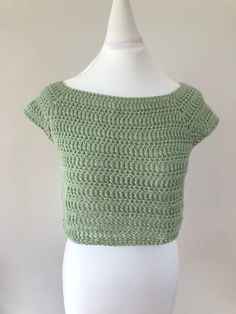 a white mannequin wearing a green crochet crop top with short sleeves