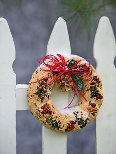 a christmas wreath hanging on a white picket fence