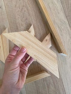 a person holding a wooden object in their hand on top of a wood floor next to other pieces of wood