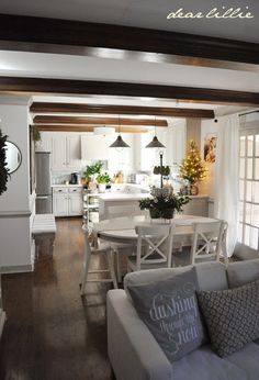 a living room filled with furniture next to a white kitchen and dining room table in front of a doorway