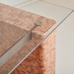 a close up of a glass and marble table with a metal bar on it's edge