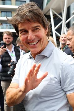 a man is smiling and waving at the camera