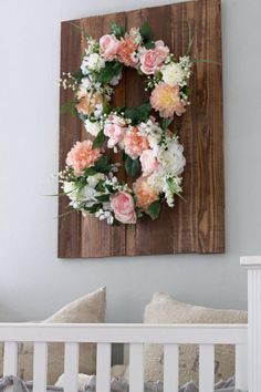 a baby's crib with a flower wreath hanging on the wall