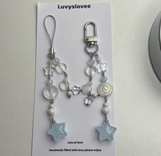 a pair of blue and white earrings with stars on them sitting next to a clock