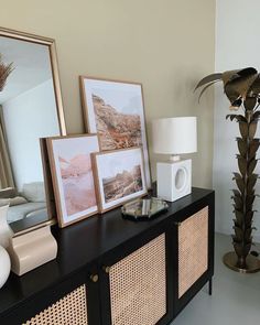 a living room with pictures and other items on the sideboard next to a lamp