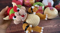 a hand holding a crocheted stuffed animal in front of some yarns on a table