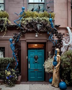 a blue front door surrounded by potted plants and other greenery in front of a building