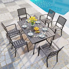 an outdoor dining table with six chairs and plates on it near a swimming pool area