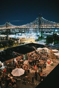 an aerial view of a city at night with lights and umbrellas on the rooftop