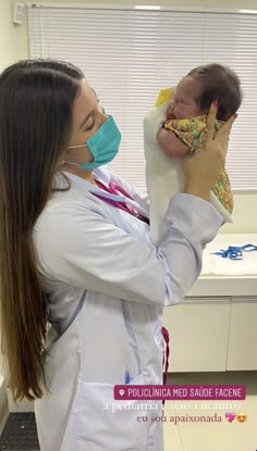 a female doctor holding a baby in her arms and wearing a face mask while looking at the camera