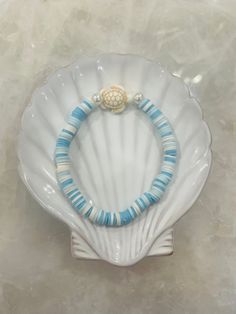 a white shell with blue beads and a gold bead on the end is sitting on a marble surface