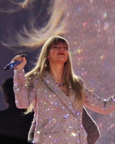 the woman is singing on stage with her hands in the air while holding a microphone