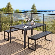 a table and bench on a deck overlooking the ocean