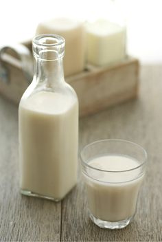 a glass and bottle of milk sitting on a table