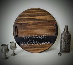 a wooden sign that says eat drink and make mementoies next to two silver goblets