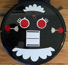 a black and white face with red eyes on a wooden floor next to a wall