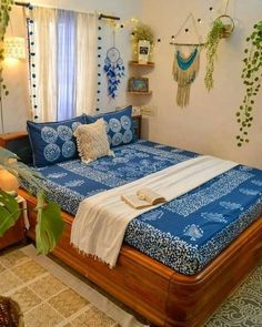 a bed with blue and white comforter in a bedroom next to a potted plant