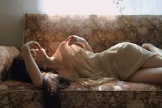 a woman laying on top of a couch next to a window