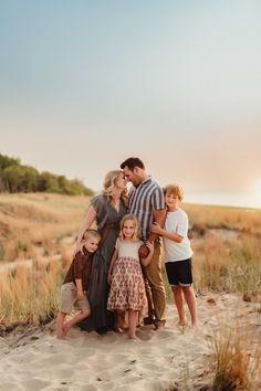 a group of people standing on top of a sandy beach next to grass and trees