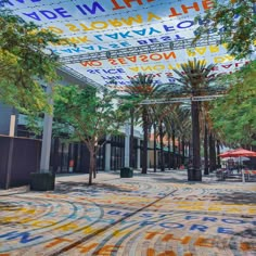 an open area with many different colored letters on the ceiling and trees in the background