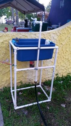 a blue and white cooler sitting on top of a grass covered field next to a yellow wall