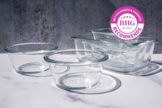 three glass dishes sitting on top of a white marble counter next to a pink sticker