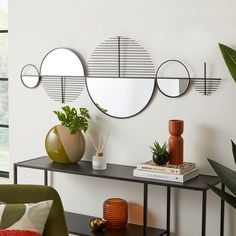 three circular mirrors mounted on the wall above a console table with plants and vases