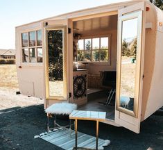 a tiny house with its door open on the ground