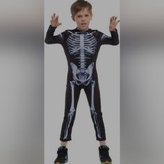 a young boy in a skeleton costume is posing for the camera with his hands up