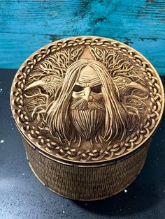 a wooden box with a man's face on the lid and braiding around it