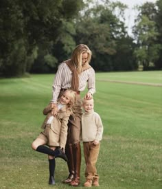 a woman and two children are standing in the grass