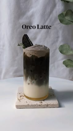 an oreo latte is sitting on top of a white table next to a green plant